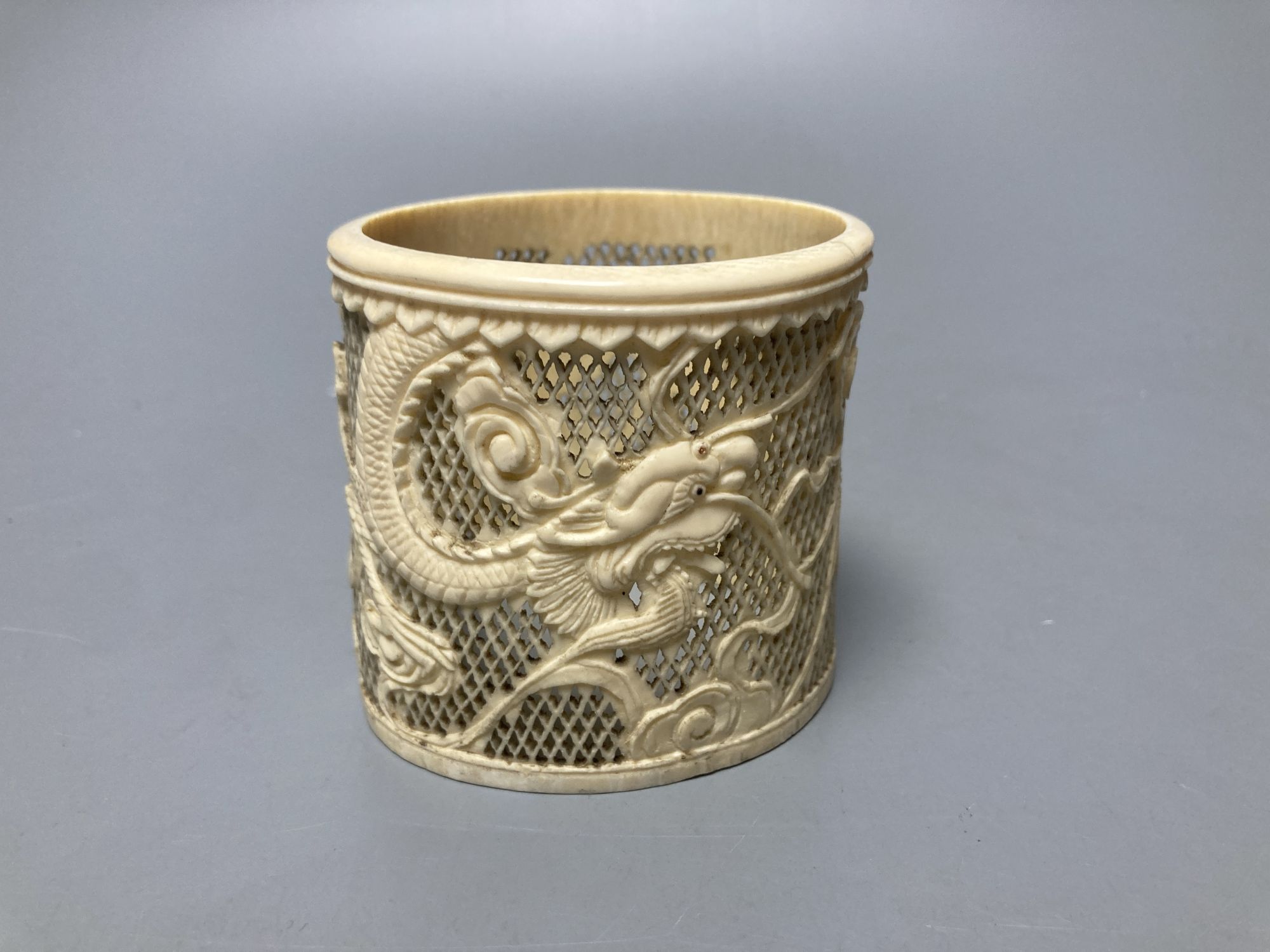 A Japanese ivory okimono of a furniture maker, signed tablet to base, Meiji period and a Chinese pierced ivory sleeve, height 6cm